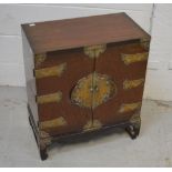 A small Chinese elm two door cabinet with engraved brass mounts and two interior drawers,