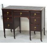 A mahogany black leather inset knee hole desk with seven drawers and terminating castors,