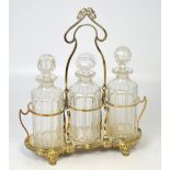 A late 19th century Art Nouveau plated framed tantalus with three cut glass decanters and tear drop