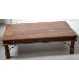 An Indian hardwood coffee table on turned baluster legs and metal supports, length 135cm.