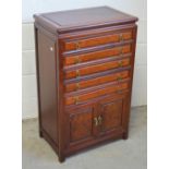 A Chinese hardwood chest of five narrow drawers above a pair of doors to base, width 56cm.