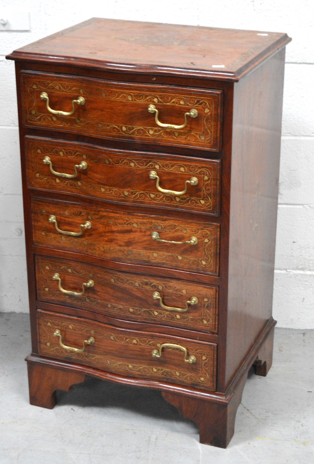 An Indian rosewood serpentine front five drawer chest of drawers inlaid with brass,