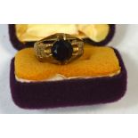 A gentleman's yellow metal dress ring set with a central red stone, size L, approx 6.4g.