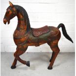 A large carved freestanding horse with carved saddle and bridle and overall floral decoration,