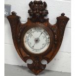 A heavily carved oak aneroid wall barometer, height 56cm.