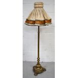 An early 20th century brass standard lamp with reeded column on shell design stand and three highly