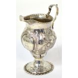 A George III hallmarked silver ewer shaped jug with scrolling handle on pedestal base,