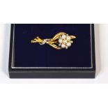 A yellow metal brooch of flower form set with seven small freshwater pearls and five tiny white