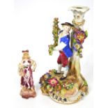 A continental porcelain figural candlestick modelled as a young boy in costume with floral