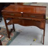 A mahogany side table with two short drawers above a shaped shelf.