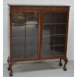 A mahogany display cabinet with twin astragal glazed doors on ball and claw feet, width 106cm.