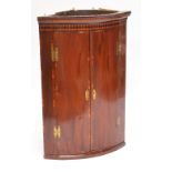 A George III mahogany and inlaid bow fronted hanging corner cupboard.