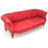 A Victorian upholstered sofa on four mahogany turned and fluted legs on ceramic castors,