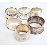 A group of five English variously hallmarked silver napkin rings including a plain bulbous example,