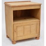 A pine bedside cabinet with moulded top above open aperture and single cupboard door raised on bun