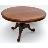 A Victorian mahogany tilt top circular breakfast table raised on three scrolling supports,
