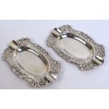 A pair of early 20th century Continental silver ashtrays of shaped oval form with foliate scroll