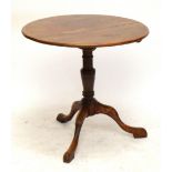 A mahogany circular tilt top occasional table on turned central column and three outswept supports,