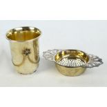 An Elizabeth II hallmarked silver tea strainer and stand with pierced shaped grips,