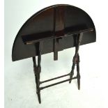 An Edwardian mahogany circular folding butler's table on turned stretchered supports,
