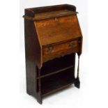 An early 20th century oak student's bureau with fall front, single drawer and shelf below,