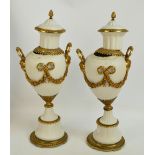 A pair of decorative porcelain and gilt metal mounted urns with twin mask handles between opposing