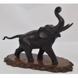 A modern bronze elephant with raised trunk and tail, with a Japanese character mark under one foot,