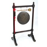 A decorative gong and strike in turned wooden frame on four outswept legs on scrolling supports and