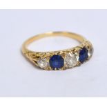 A yellow metal diamond and sapphire dress ring with two oval sapphires alternating with three