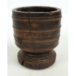 An 18th century turned soft wood footed mortar with horizontal turned bands to the side,