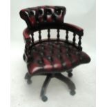 A modern ox blood red leather button upholstered revolving office/desk chair.