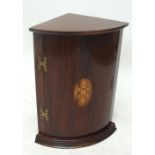A reproduction mahogany bowfronted hanging corner cupboard of small proportions with inlaid oval