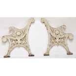 A pair of painted cast iron garden bench ends, each with pierced foliate design and scrolling arms.