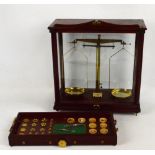 A mahogany cased set of laboratory scales mounted on a shelf set with a large collection of