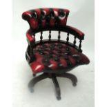 A modern ox blood red leather button upholstered revolving office/desk chair.