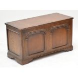 An early 20th century oak blanket box with two carved panels to the front, on bracket feet,