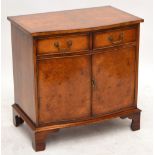 A reproduction serpentine front cabinet with two drawers above a pair of doors, on bracket feet,