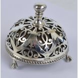 A George V hallmarked silver counter bell with circular domed pierced scroll decorated body,