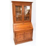 A modern pine bureau bookcase with glazed upper section and fall front above two cupboard doors to