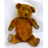 A mid 20th century plush teddy bear with plastic eyes, replaced pads, and growler, height 56cm.