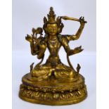 A 19th century Hindu gilded figure holding a sword in one of the four arms and sat cross-legged on