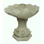 A modern concrete scallop shell moulded bird bath.