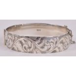 An Elizabeth II hallmarked silver hinged snap bangle with foliate engraved decoration, London 1975,