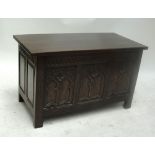 An oak blanket box with Gothic carved three-panel front, width 108.5cm.