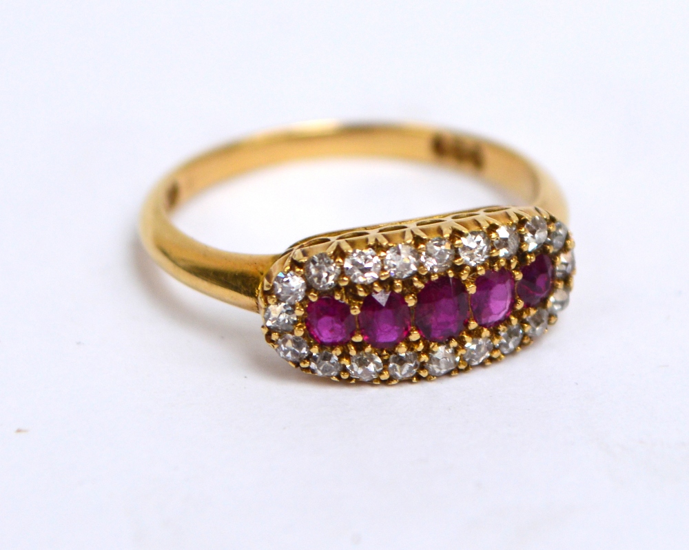 An 18ct yellow gold dress ring with five graduated oval rubies surrounded by twenty small diamonds,