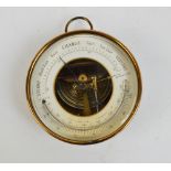 An early 20th century lacquered brass cased circular aneroid barometer with ring loop attachment,