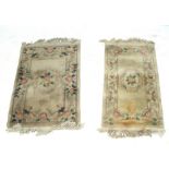 Two similar beige floral decorated carpets, 132 x 77cm and 129 x 62cm (2).