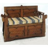 An early 20th oak box seat hall settle with hinged seat and twin side apertures for