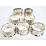 A group of seven English variously hallmarked silver engine turned decorated circular napkin rings