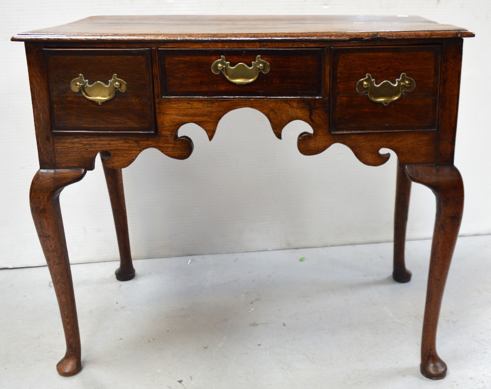 An 18th century oak lowboy with three drawers and shaped apron on pad feet, width 83cm.